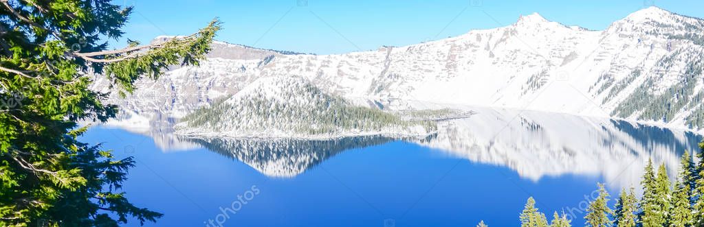 Panoramic green pine tree lush and reflection of snowcap mountain with Wizard Island on Crater Lake