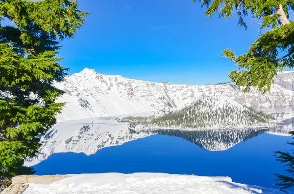 Viewpoint cliff at Crater Lake with pine tree lush and reflection of snowcap mountain and Wizard Island — Stock Photo, Image