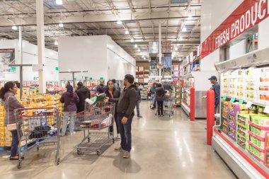 Meşgul insanlar, Kara Cuma 'daki Costco toptan satış mağazasında taze ürünler stokluyor.