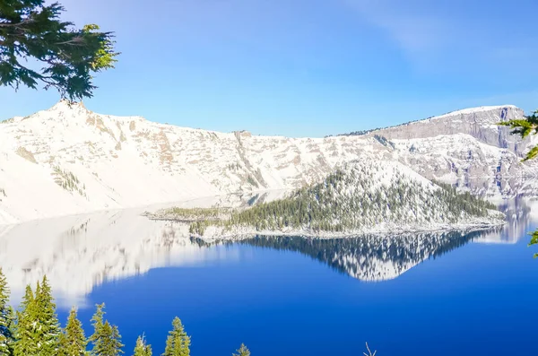 Groene dennenboom weelderig en reflectie van snowcap berg met Wizard Island op Crater Lake — Stockfoto