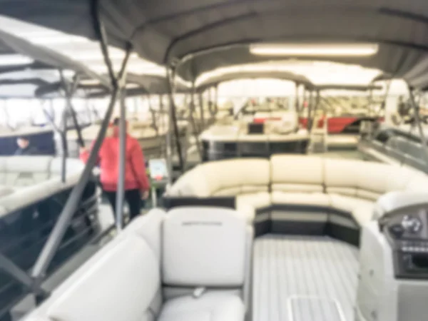 Blurred motion Asian customers in warm clothes try test driving at large dealer selling variety of new and used boats near Dallas, Texas, USA. Recreational boat buying and servicing concept