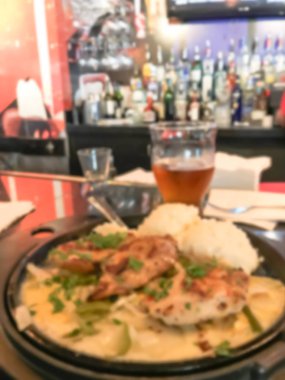 Bulanık hareket tavuk salatası, bira kupa ve arka planda alkol içecekler çeşitli bar sayacı.