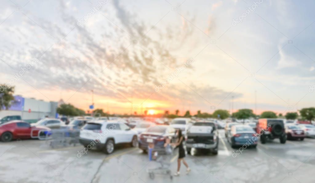 Motion blurred customer with shopping cart walking at parking lots of grocery store near Dallas, Texas, America. Beautiful and dramatic sunset cloud