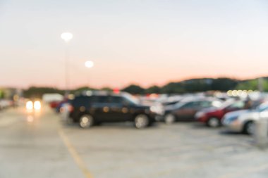 Houston, Teksas, Usa 'daki modern alışveriş merkezinin bulanık otoparkı. Dış görünüş alışveriş merkezi kompleksi, arka planda ışık direkleri, açık otoparkta sıra sıra giden arabalar.