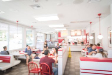 Bulanık görüntü Austin, Teksas, ABD'de kompakt bir fast food restoran. İnsanlar sos, ketçap hizmet ve hamburger, kızarmış patates kızartması ve şeker içecek ile öğle yemeği zevk. Bokeh soyut ile doğal ışık.