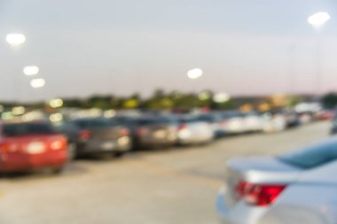 Houston, Teksas, Usa 'daki modern alışveriş merkezinin bulanık otoparkı. Dış görünüş alışveriş merkezi kompleksi, arka planda ışık direkleri, açık otoparkta sıra sıra giden arabalar.