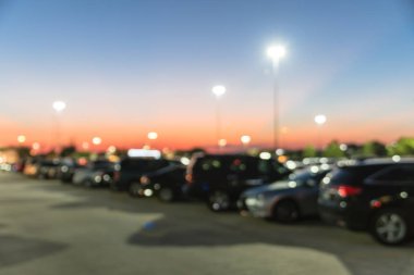 Houston, Teksas, Usa 'daki modern alışveriş merkezinin bulanık otoparkı. Dış görünüş alışveriş merkezi kompleksi, arka planda ışık direkleri, açık otoparkta sıra sıra giden arabalar.