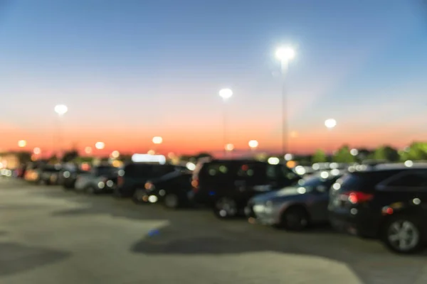 Abstract blurred parking lot of modern shopping center in Houston, Texas, USA. Exterior view mall complex with row of cars in outdoor uncovered parking, bokeh light poles in background