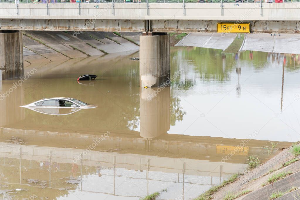 A 15 feet and 9 inches tollway bridge with flooded cars underneath. Swamped sedan vehicles under highway road near downtown Houston, Texas.