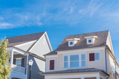 Dallas, Teksas, Usa 'da tipik bir evin ikinci katındaki çatı pencereleri. Tavan arası boşluğunun dışında, bulut mavisi gökyüzünün altında yıpranmış iskan evlerinin kaplamaları var.