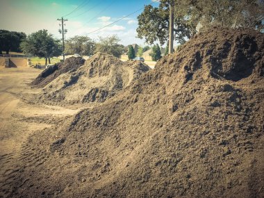 Giant pile of compost, mulch, sand, gravel, soil, stone for bulk sale. Locally sourced and blended organic feed stocks. Landscape and gardening materials wholesaler near Dallas, Texas, USA. clipart