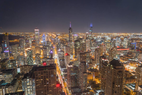 Aerial view downtown Chicago illuminated at blue hour. Waterfront skyscrapers and Lake Michigan is available on the left.
