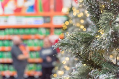 Arka planda bulanık müşteri alışverişi olan seçici odak beyaz yapay Xmas ağacı