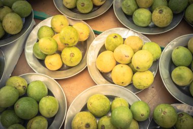 Heap of fresh raw green and ripe guavas on aluminium trays at Singapore local market