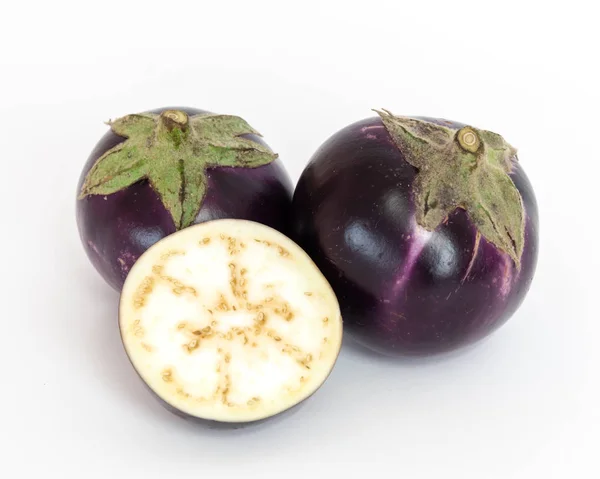 Studio shot of two organic and a half-cut of violet round Thai eggplants isolated on white — Stok fotoğraf