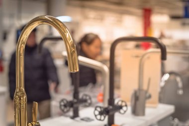 Blurry customer shopping for kitchen faucets at furniture showroom store in Texas, USA