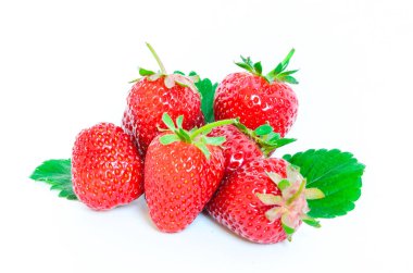 Çilek yığını, yarısı kesilmiş ve yaprakları beyazın üzerinde.