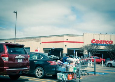Amerikalı bir aile, Costco 'yu alışveriş arabalarından gerekli malzemelerin bagajına koyuyor.
