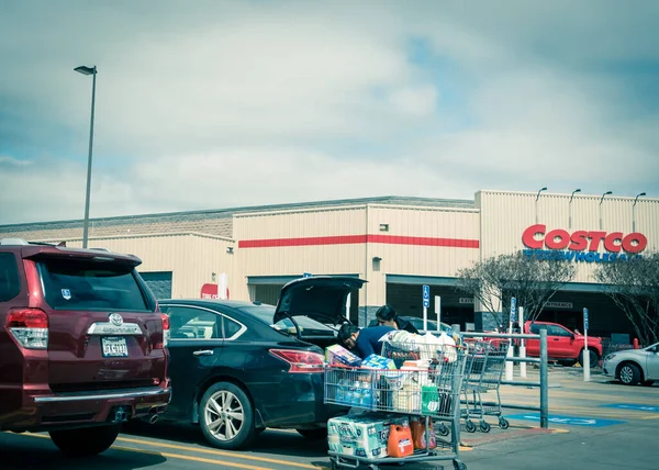 Una carga familiar estadounidense Costco comestibles en el maletero del coche de carros de compras llenos de necesidades esenciales — Foto de Stock