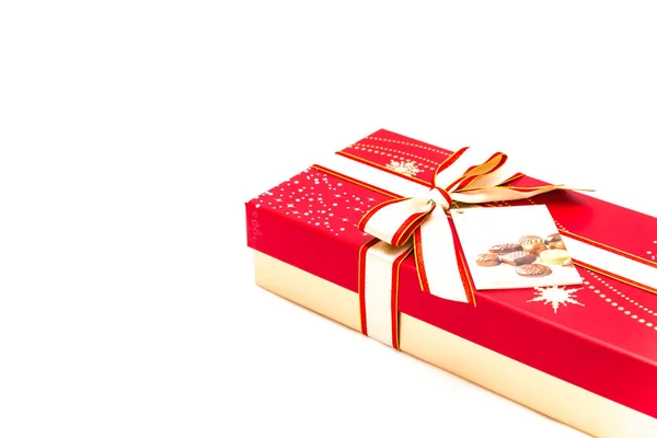 Red chocolate box with tag label and red yellow bow ribbon isolated on white — Stock Photo, Image