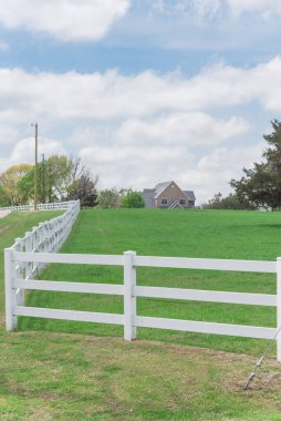 Ennis, Teksas, ABD 'de arka planda çözünmüş çiftlik evi çiftliği olan sığ, uzun beyaz çitler.