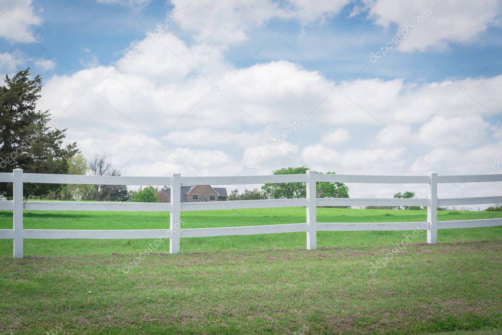 Shallow DOF long white fence with defocused farm house ranch in background in Ennis, Texas, USA