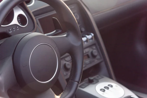 Внутри водительское сиденье суперкара с рулевым колесом и современными функциями на приборной панели — стоковое фото