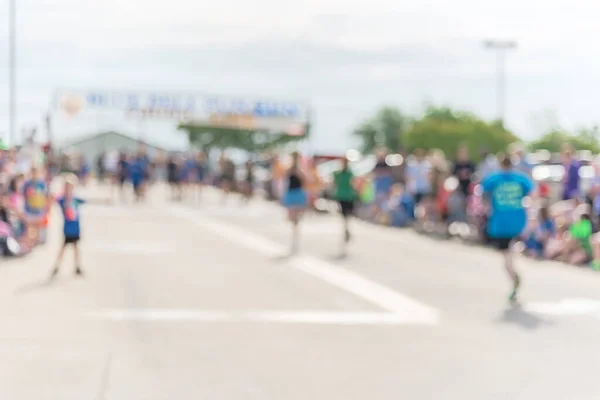 Blurry background diverse runner near finish line with crowded cheering at running event in Texas, USA