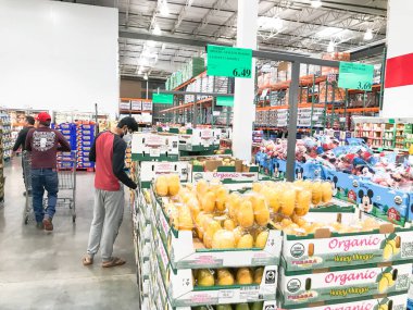 Coronavirus sırasında maske takan müşterilerle birlikte Costco 'da taze meyve ürünleri üretiyor.