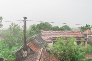 Kuzey Vietnam 'ın kırsal kesiminde yağmurlu bir günde eski kil çatı kiremitleri olan geleneksel bir ev.