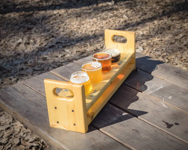 Bandeja de amostragem de voo de cerveja com vista superior na mesa de piquenique de madeira ao ar livre no jardim da cervejaria no Texas, EUA — Fotografia de Stock