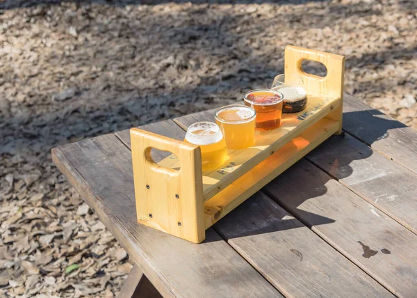 Bandeja de amostragem de voo de cerveja com vista superior na mesa de piquenique de madeira ao ar livre no jardim da cervejaria no Texas, EUA — Fotografia de Stock