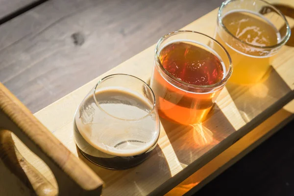 Top view mixed of draft beers in tasting sampler tray on wooden picnic table of brewery in Texas, USA — Stock Photo, Image
