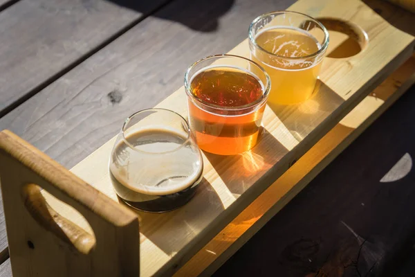 Mezcla de bebidas artesanales en paleta de la bandeja de degustación con el nombre de la cerveza en un entorno natural — Foto de Stock