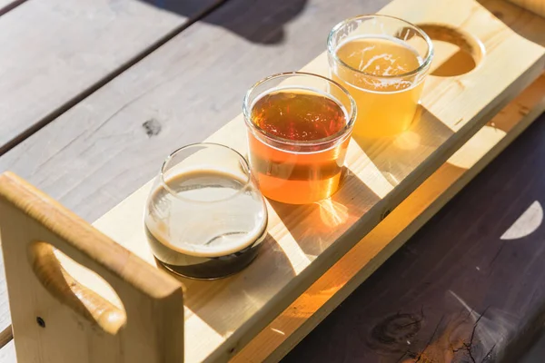 Vista superior mezclada de cervezas de barril en bandeja degustación de muestras en mesa de picnic de madera de cervecería en Texas, EE.UU. — Foto de Stock