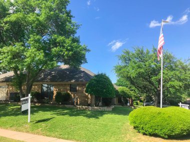 Amerikan bayraklı köşe evi ve Dallas, Teksas, ABD 'de mahalle banliyölerinde satılık tabelası.