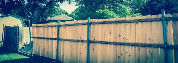 Panoramic new wooden fence near collapsed slats in backyard of residential house with shed