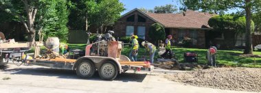 Maskeli panoramik inşaat işçileri Dallas, Teksas, ABD banliyölerindeki kaldırımları onarıyor.