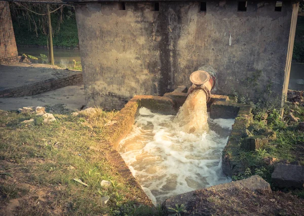 Sistema de bombeo de riego típico asiático con burbujas que fluyen en el agua que corre desde un oleoducto rústico en Vietnam — Foto de Stock