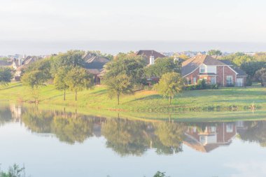Dallas, Teksas, ABD yakınlarındaki sakin göl manzaralı banliyö evleri yansıyor.