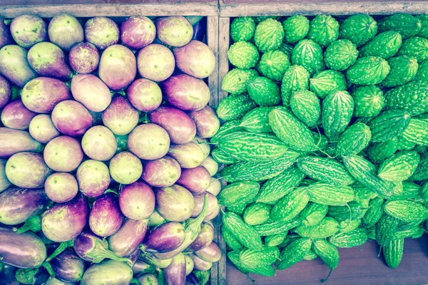 Levendige groene bittere meloen en paarse Aziatische aubergines op groentestand in Little India, Singapore — Stockfoto