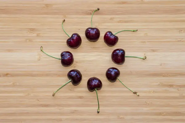 Cerezas rojas oscuras maduras en círculo sobre tabla de madera — Foto de Stock