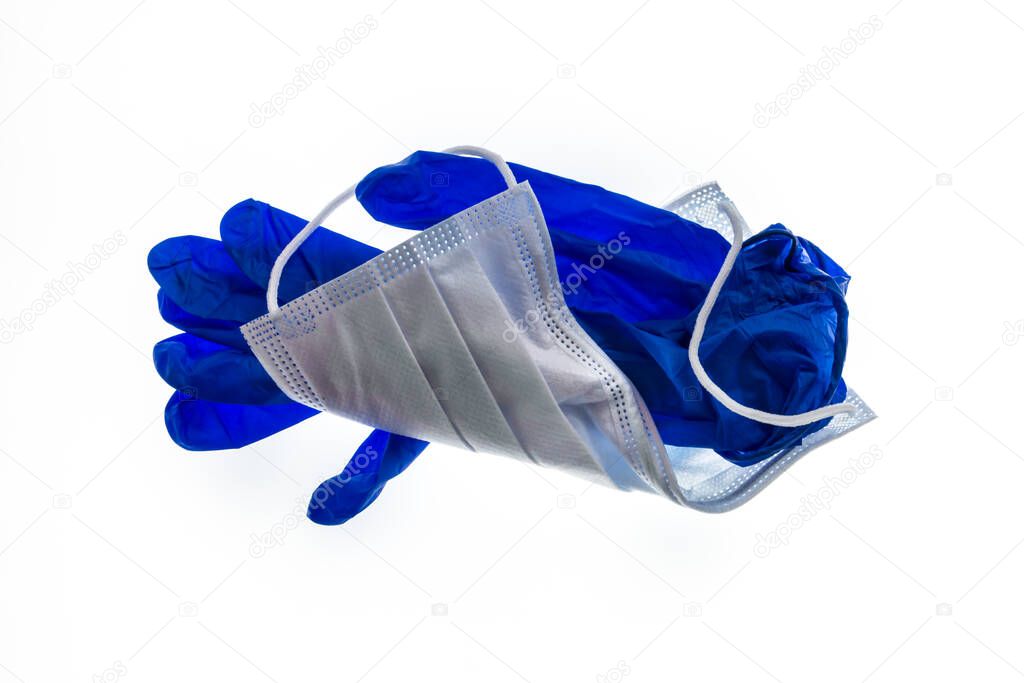crumpled surgical face mask and blue latex surgical gloves on white background