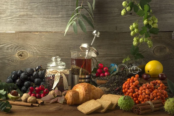 Horký čaj konvici na dřevěné pozadí obklopen podzimní plody — Stock fotografie