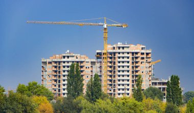 İnşaat vinçleri ve yüksek katlı bina inşaat mavi gökyüzü altında.