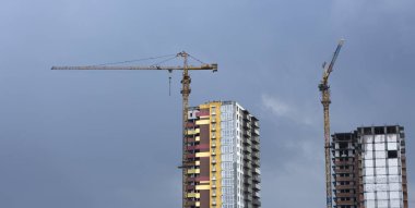 İnşaat vinçleri ve yüksek katlı bina inşaat mavi gökyüzü altında.