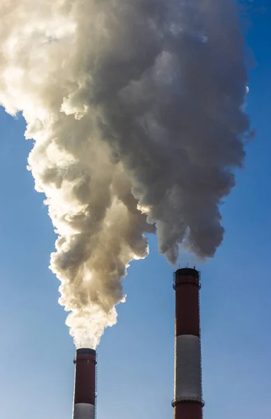 De pijp van de plant straalt schadelijke stoffen in de atmosfeer. Close-up op een hemelachtergrond — Stockfoto