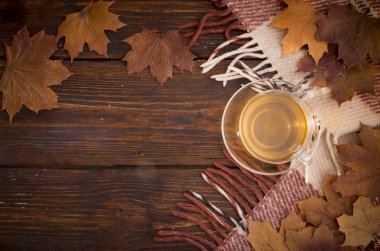 Soluk boya ve kareli ekose ile eski kurullarında bir fincan çay ve akçaağaç yaprakları