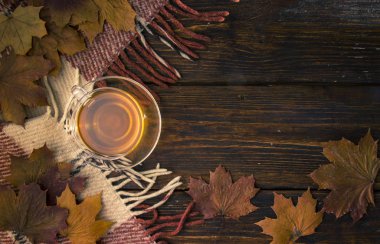 Soluk boya ve kareli ekose ile eski kurullarında bir fincan çay ve akçaağaç yaprakları