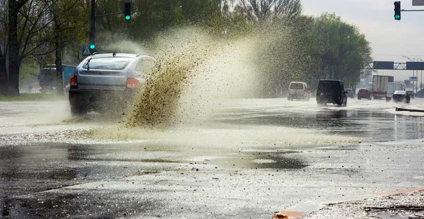 Salpicar por un coche a medida que pasa por el agua de inundación — Foto de Stock